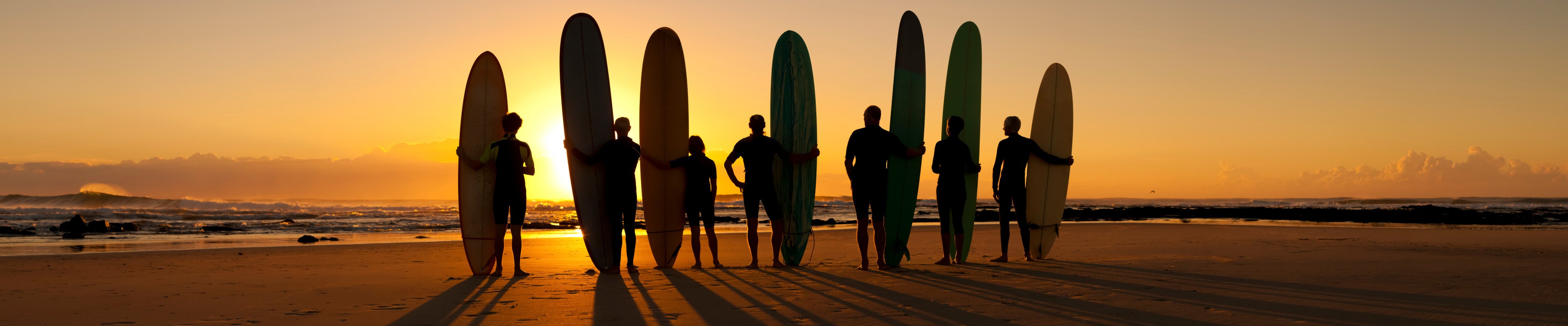 Surfers on beach at sunset iStock 171252100 crop 3840x800 94472207 7060 40a9 a4ef c5b518c1b52d