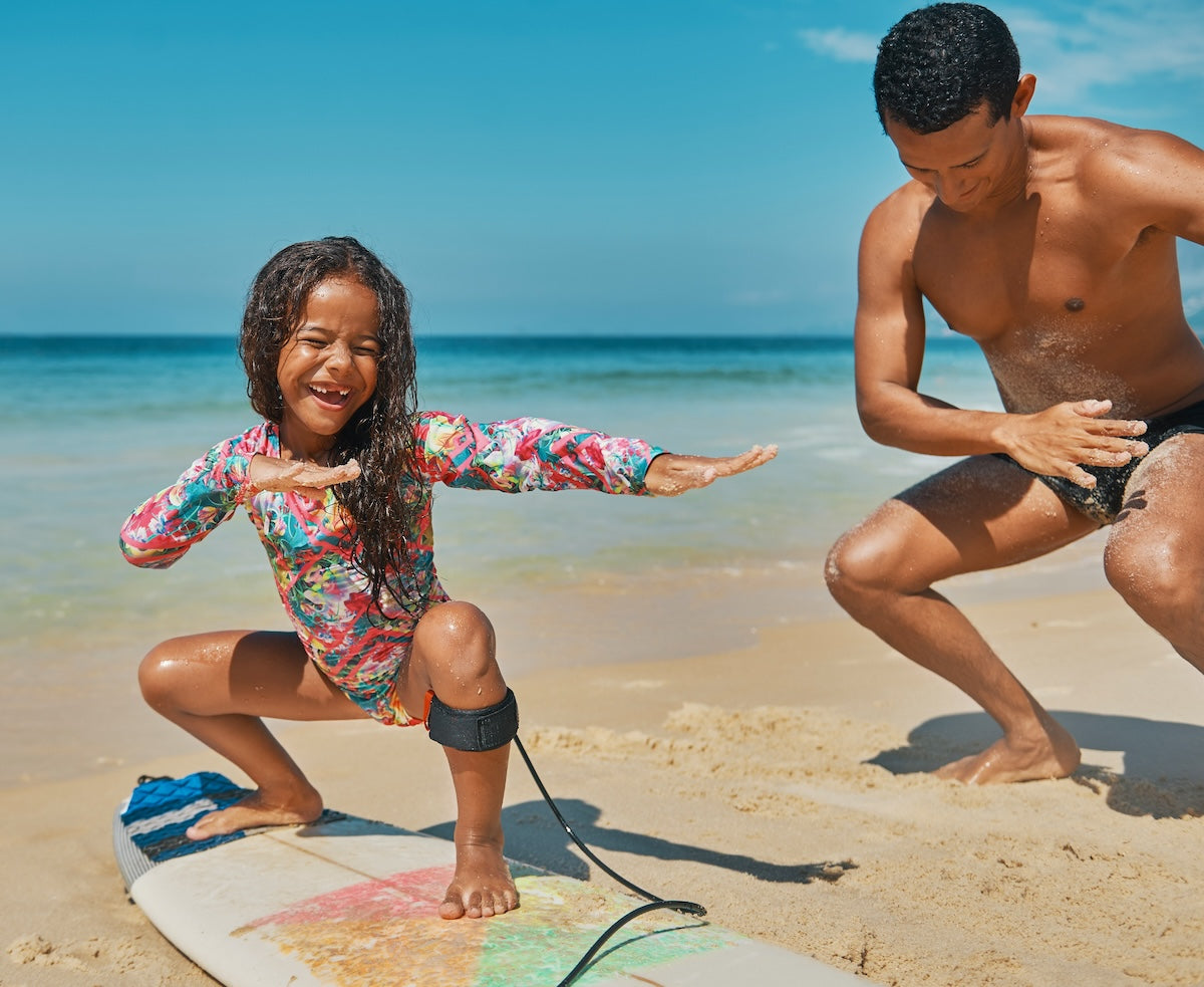 Young girl surfer with dad on beach iStock 1204429206 LR adjusted crop compressed 5130599a e603 4a37 bb84 27d873a6b99a